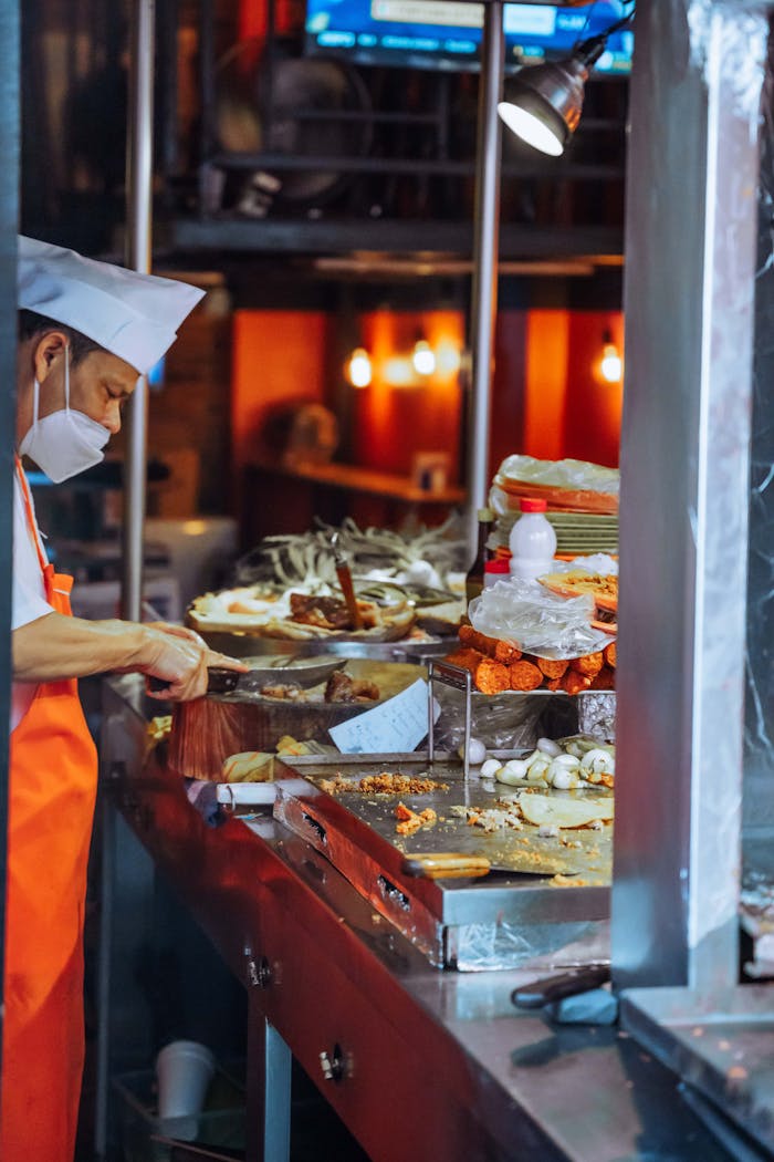 Chef preparing street food with vibrant ingredients at night market stall.
